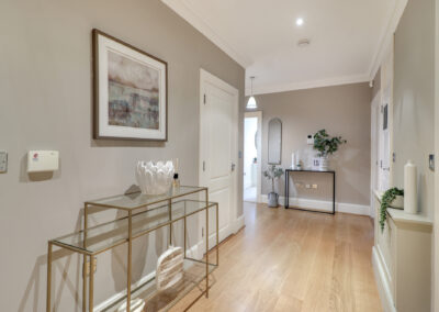 Professionally staged home by Beau Property Home Staging. Show home hallway featuring side table with plants and ornaments