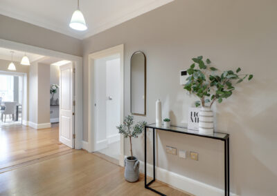 Professionally staged home by Beau Property Home Staging. Show home hallway featuring side table with plants and ornaments
