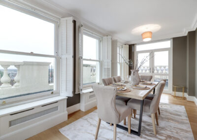 Professionally staged home by Beau Property Home Staging. Show home dining area featuring set table, lighting, radiator covers and hanging artwork