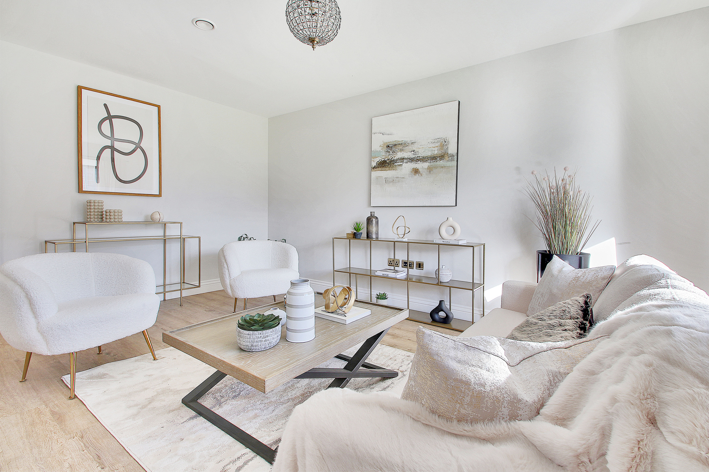 Professionally staged home by Beau Property Home Staging. Show home lounge featuring sofa with throw, designer chairs & staged coffee table. Artwork, shelving units and plants around the room.