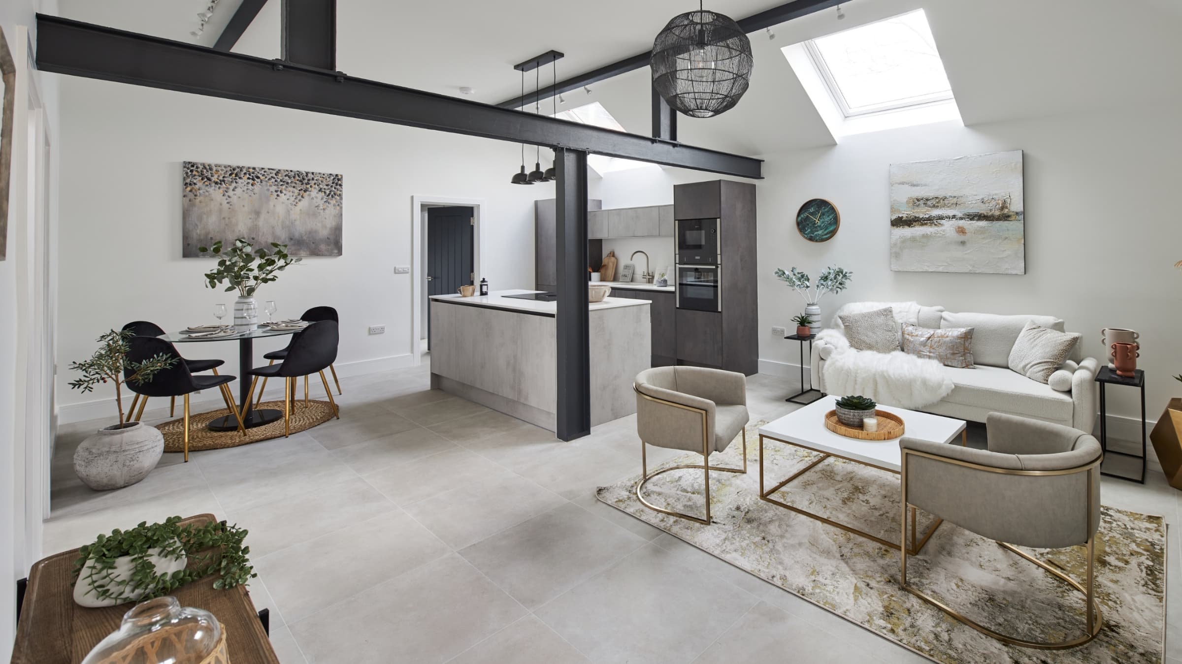 Professionally staged open plan kitchen & living room featuring sleek modern artwork, designer furniture. Light and airy feel with a few dark details and gold accents.